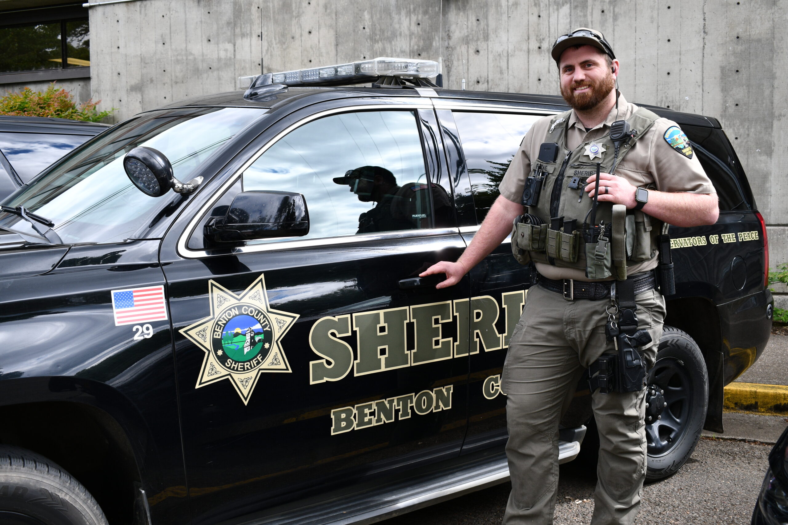 A Benton County Sheriff's Deputy stands next to his patrol car.